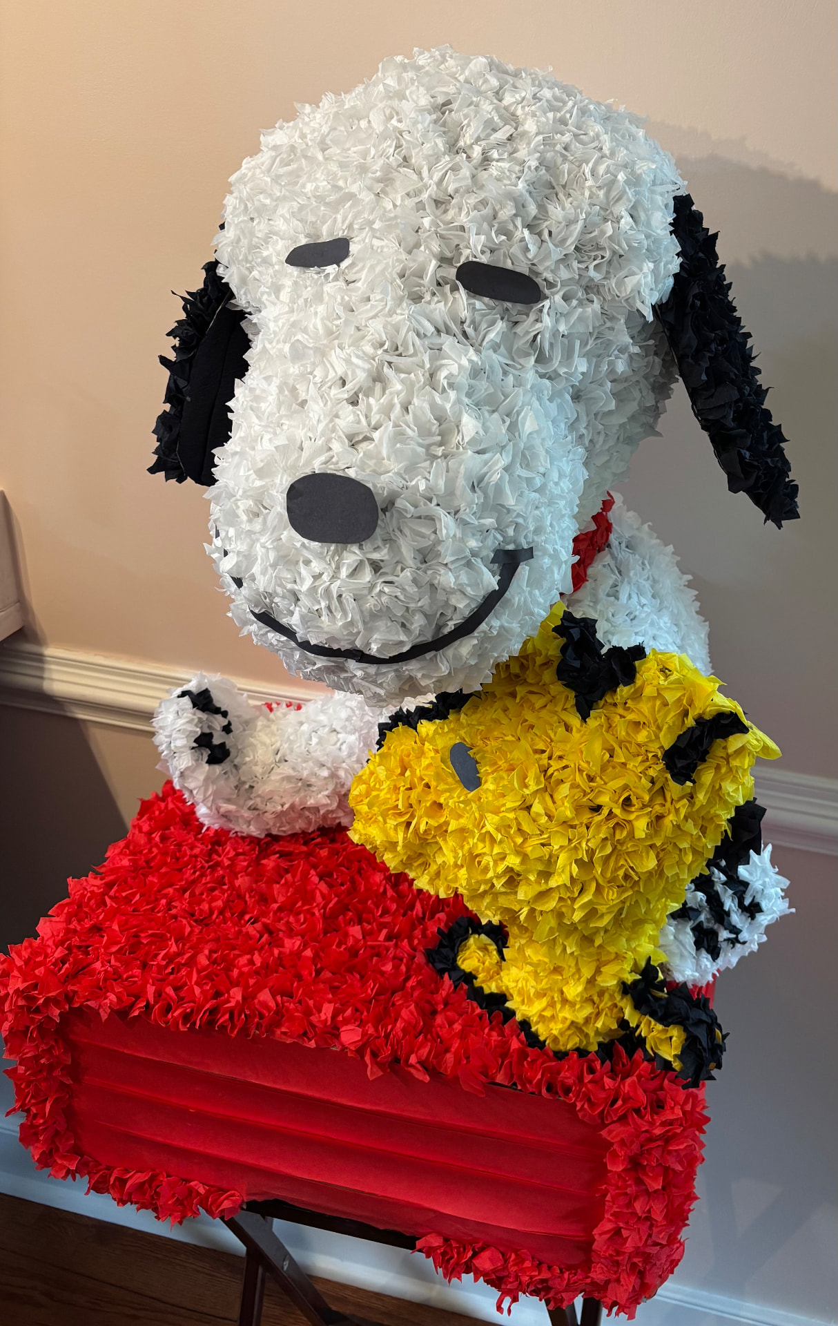 Handmade Snoopy-inspired piñata with Woodstock on a red doghouse, made from layered tissue paper