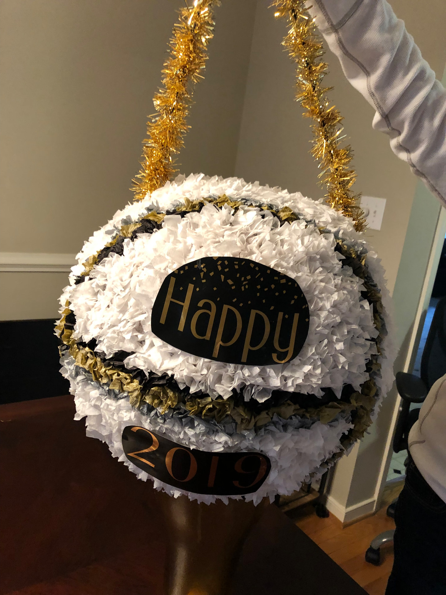 Handmade New Year's Eve ball piñata in white, gold, and black tissue paper with 'Happy 2019' lettering